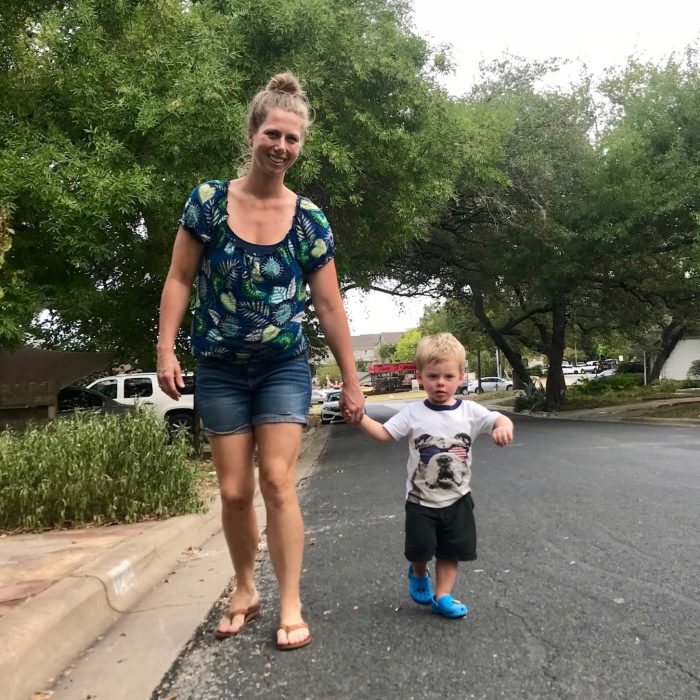 mom and toddler boy walking on street in neighborhood