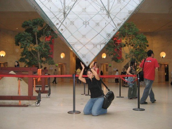 The inverted pyramid of the Louvre lobby appears to hover over the author's head while her hands pose to appear to hold it up. Taken during her time as an au pair in Paris.