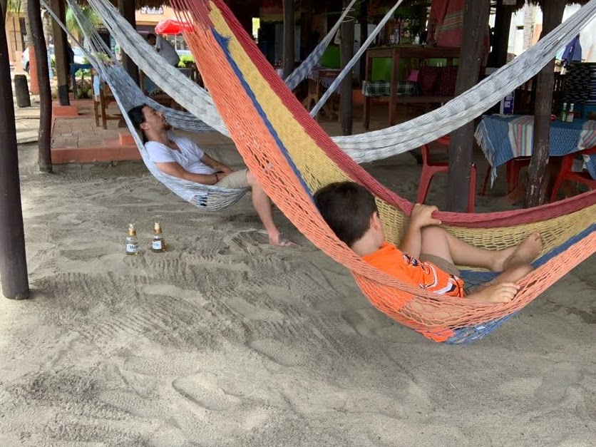 The author's son takes his nap in a beachside hammock next to a tourist sharing the same experience.