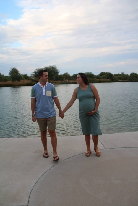 Pregnant woman and man walk hand and hand in front