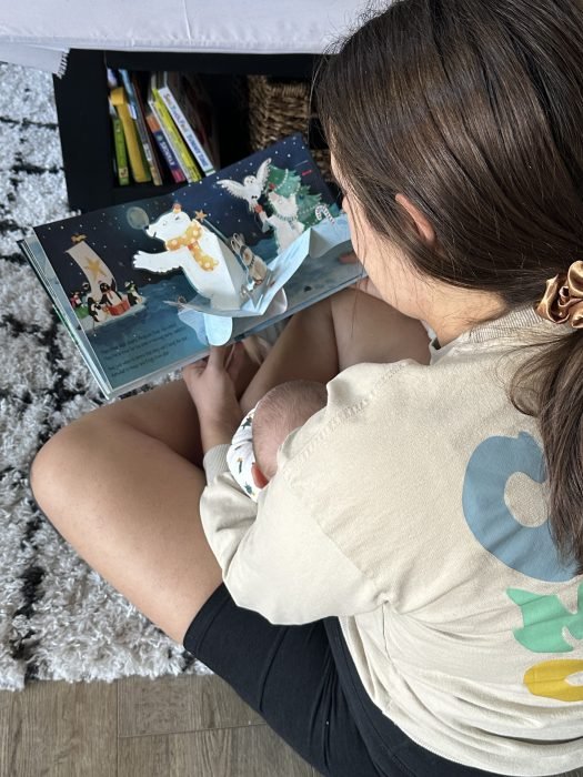 We see the back of a woman’s and baby’s heads as they read a pop up book